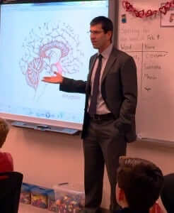 Doug Allen gestures towards a drawing of the human brain as he teaches a classroom of teen students. 