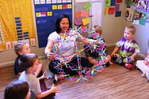 Renee sits with children using a Hoberman sphere to breathe mindfully. 