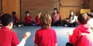 Cindy sits in a circle with students.